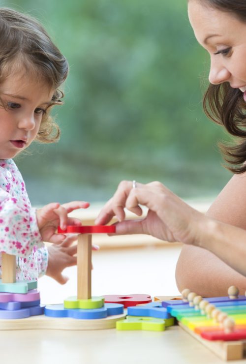 Nursery worker playing with little toddler.